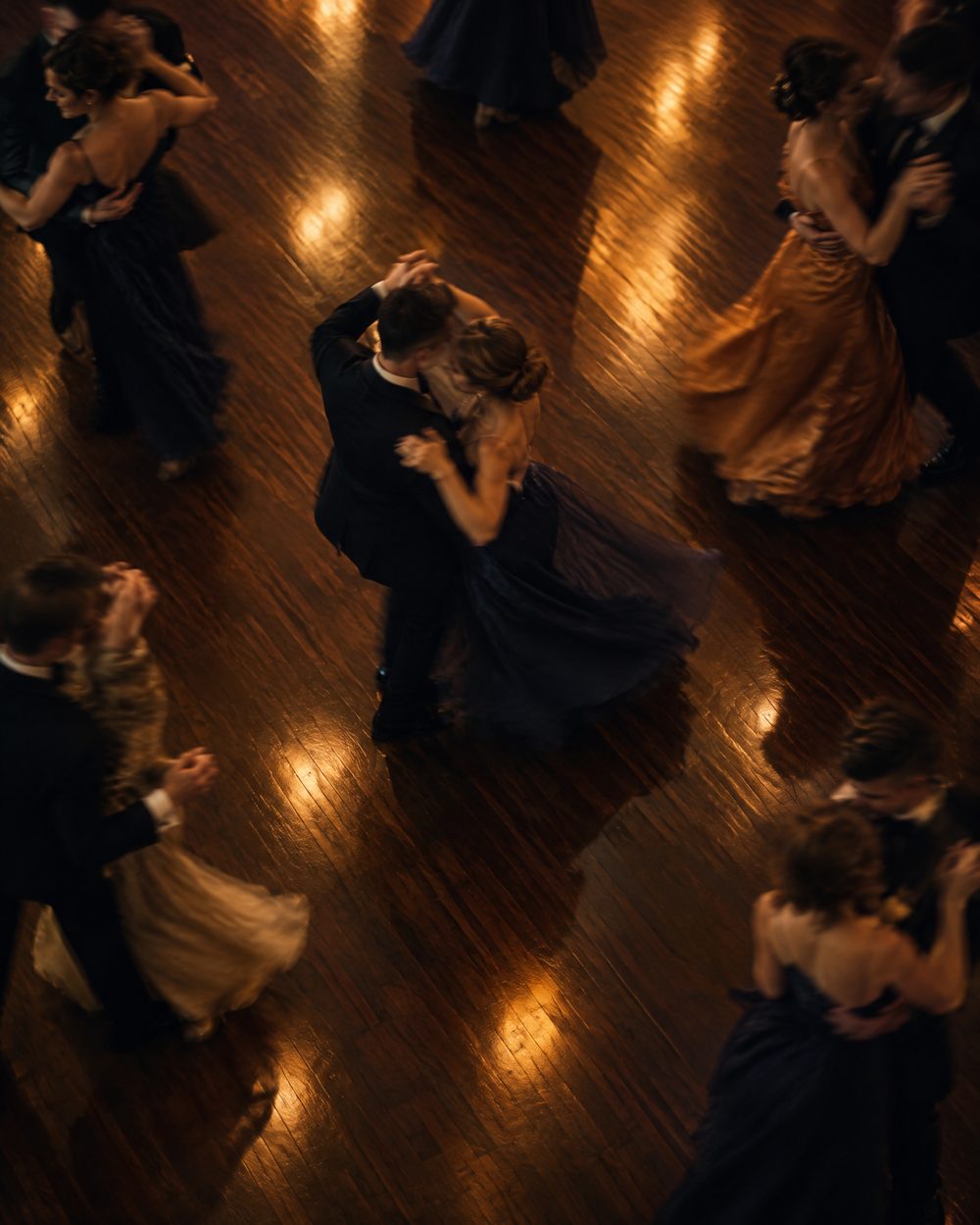 Couples dancing on a polished wooden dance floor, seen from above